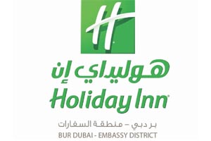 Table with chairs and flowers located near lounge area and kitchen in spacious room of contemporary apartment